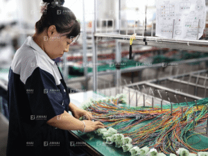 Workers are conducting connector pull tests on custom wiring harnesses.